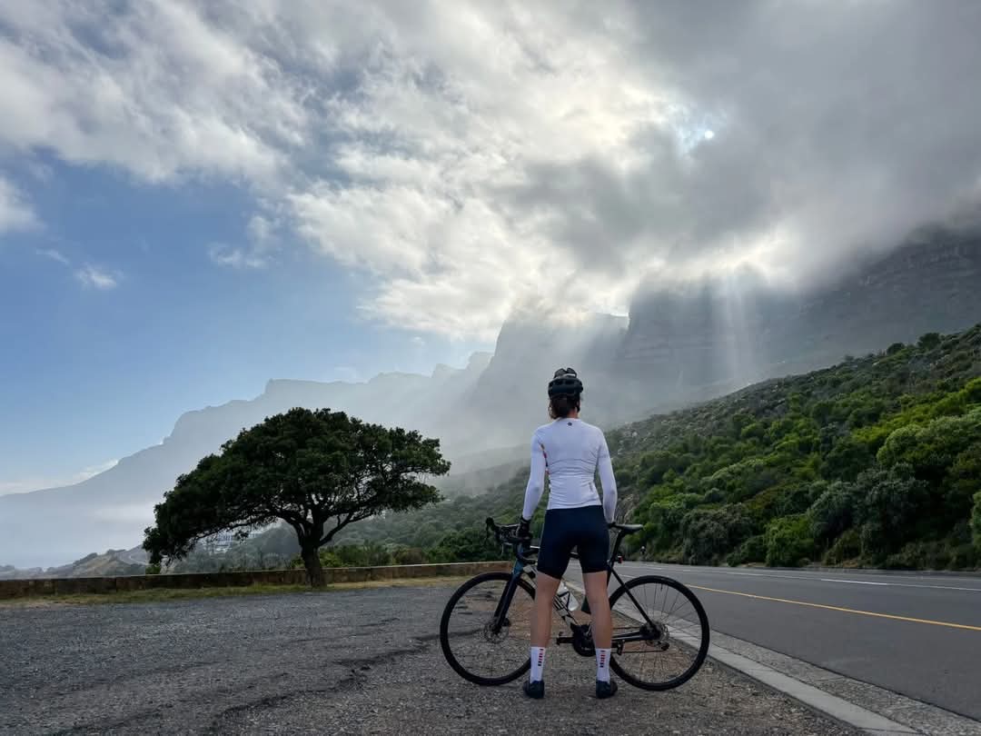 a wellness woman standing on a road with a bicycle